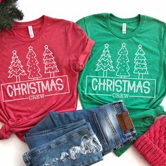 three t - shirts with christmas trees on them are sitting next to a pair of jeans