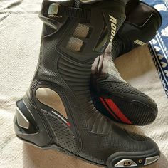 a pair of black and red shoes on top of a bed next to a blanket