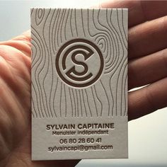 a person holding up a business card with the letter s on it in their hand