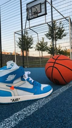 a pair of sneakers sitting on top of a basketball court next to a basket ball