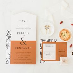 the wedding stationery is laid out on top of each other, including an orange and white menu