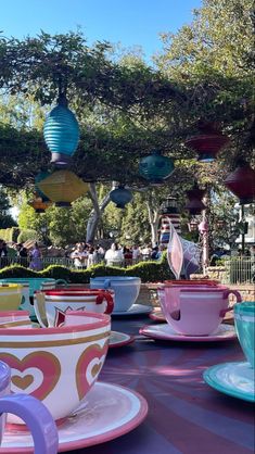 colorful tea cups and saucers are lined up on a table in an amusement park