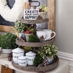 three tiered trays filled with coffee cups and plants on top of a table