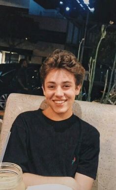 a young man sitting at a table with a plate of food in front of him