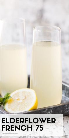 two glasses of elderflower french 75 are on a tray next to a lemon slice