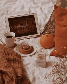 a table topped with an ipad next to a cup of coffee and cinnamon buns