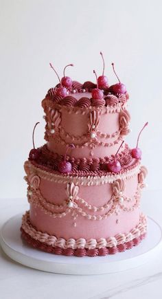 a three tiered cake with pink frosting and cherries