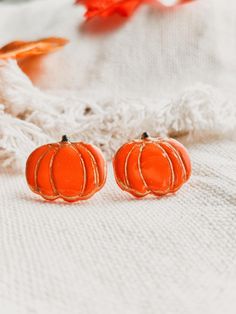 two small orange pumpkins sitting on top of a white blanket next to an orange flower