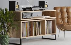 a record player sitting on top of a wooden shelf next to a chair and potted plant