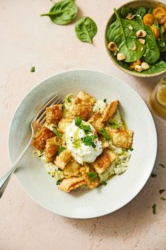 a white plate topped with food next to a bowl of salad