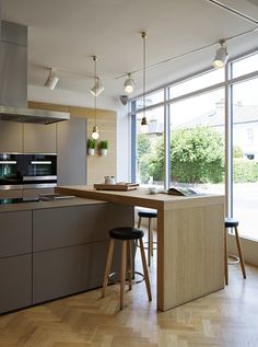 a kitchen with an island and stools in front of large windows that look out onto the street