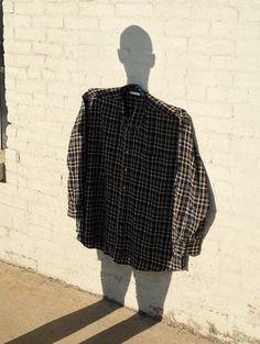 the shadow of a man's head is cast on a shirt hanging up against a brick wall