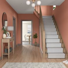 the hallway is painted in peach and has white carpet on the wooden floor, along with stairs leading to another room