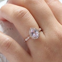 a close up of a person's hand with a pink ring on their finger