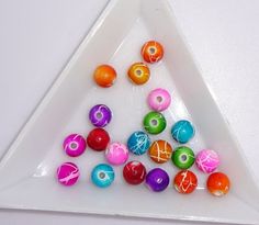 there are many different colored balls in the triangle on the white table top and one is orange, pink, green, blue