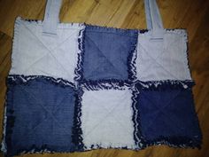 a blue and white patchwork tote bag sitting on top of a wooden floor