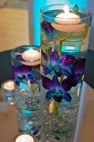 there is a vase with flowers and candles on the table in front of some glasses