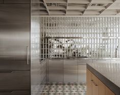 a kitchen with stainless steel appliances and tile flooring, along with an island in the middle