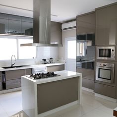 a modern kitchen with stainless steel appliances and white counter tops, along with an island in the middle