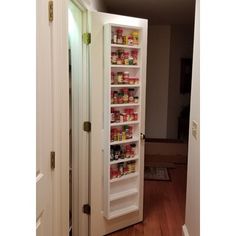 an open pantry door with food in the bottom shelf and on the inside wall is a white refrigerator