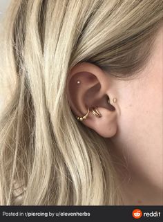 a woman's ear is shown with two gold piercings on the top of it