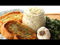 bread, garlic and herbs sit on a cutting board next to a jar of mayonnaise