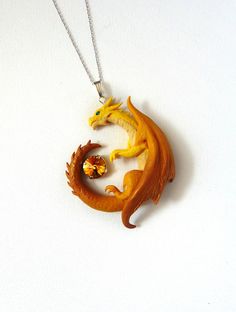 a necklace with two yellow dragon heads hanging from it's side on a white surface