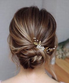 a woman wearing a hair comb with flowers in it's back and her hair pulled up into a low bun