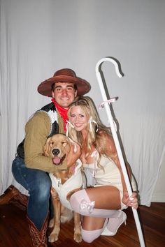 a man and woman pose with a dog in front of a white backdrop while holding an umbrella