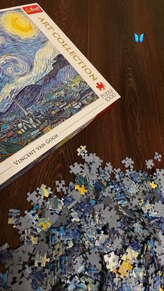 a puzzle is laying on the floor next to a book with an image of starry night