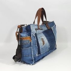 a bag made out of old jeans with leather handles and zippers on the sides