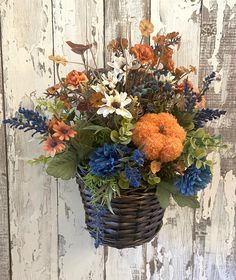 a basket filled with lots of flowers on top of a wooden floor next to a wall