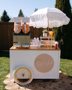 an ice cream cart is set up in the yard with umbrellas and drinks on it