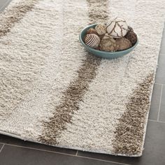 a bowl filled with rocks sitting on top of a white rug in a living room