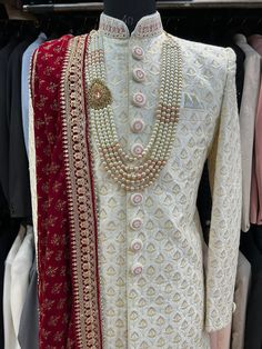 a white suit with red and gold trimmings on display in a clothing store