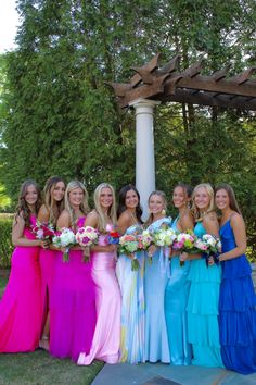 a group of women standing next to each other in long dresses and holding bouquets