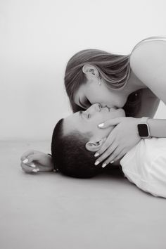 black and white photograph of a woman kissing a man's head on the floor