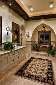 a large bathroom with an ornate rug and tub in the center, along with two sinks