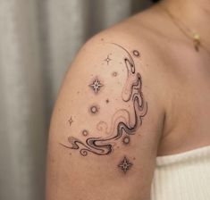 a woman with a tattoo on her shoulder has a crescent moon and stars in the sky