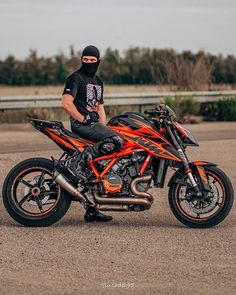 a man sitting on top of a motorcycle wearing a black and orange outfit with a helmet