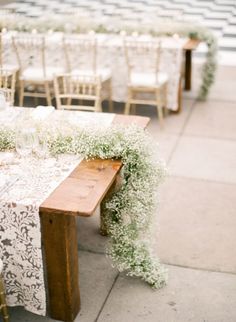 the table is set up with white flowers and greenery for an elegant wedding reception