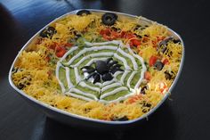 a spider web cake is decorated with cheese, black olives and other toppings