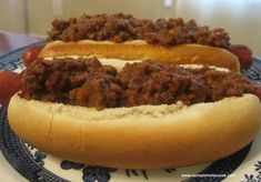 two chili dogs on a plate with buns