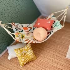 a hammock filled with pillows on top of a wooden floor next to a pillow