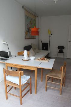 a kitchen table with two chairs and a laptop on it, in front of a couch