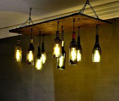 a bunch of wine bottles hanging from a light fixture with lights on them in a room