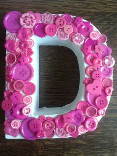 the letter d is decorated with pink and white buttons