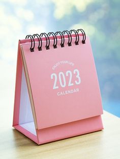 a pink desk calendar sitting on top of a wooden table