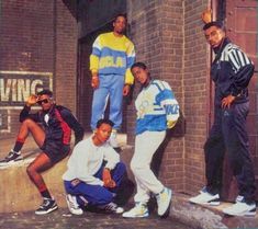 four young men posing in front of a brick building