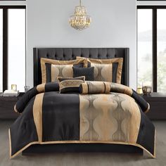 a bed with black and gold comforters in a room next to a chandelier